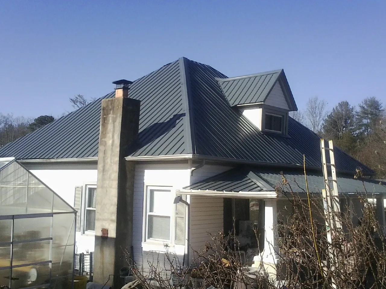 Dark blue standing seam metal roof on a white farmhouse with dormer — Slate & Tile Roof Repair by Roofing Brothers in Brierfield