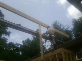 Carpenter setting a ridge beam over a new addition frame — Ice Dam Removal by Roofing Brothers in Brierfield