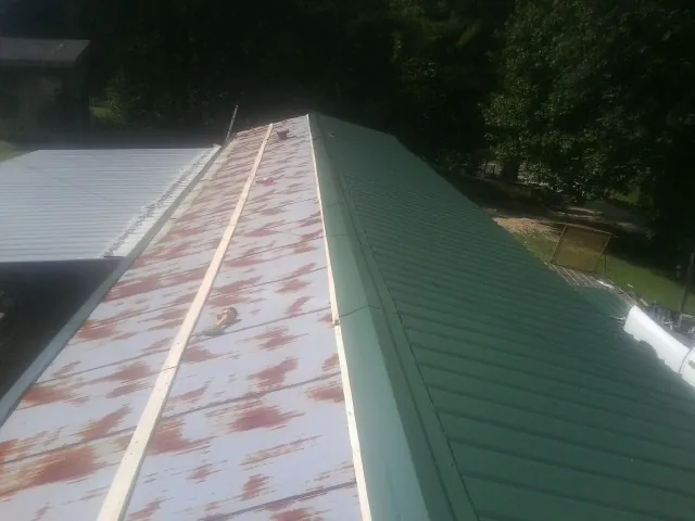 Old rusted panels beside newly installed green metal roofing — Wind Damage Roof Repair by Roofing Brothers in Brierfield