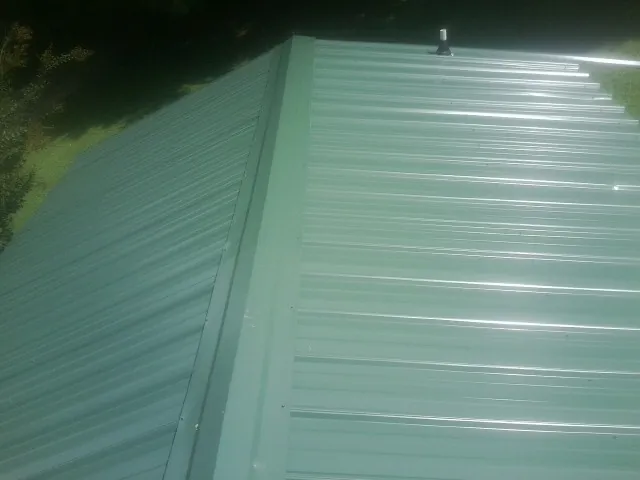 New green metal panels meeting at the ridge of a roof — Flat Roof Repair work by our crew in Brierfield