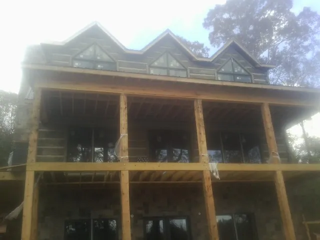 Dormers and porch framing on a large log home under construction — Roof Coating work by our crew in Brierfield
