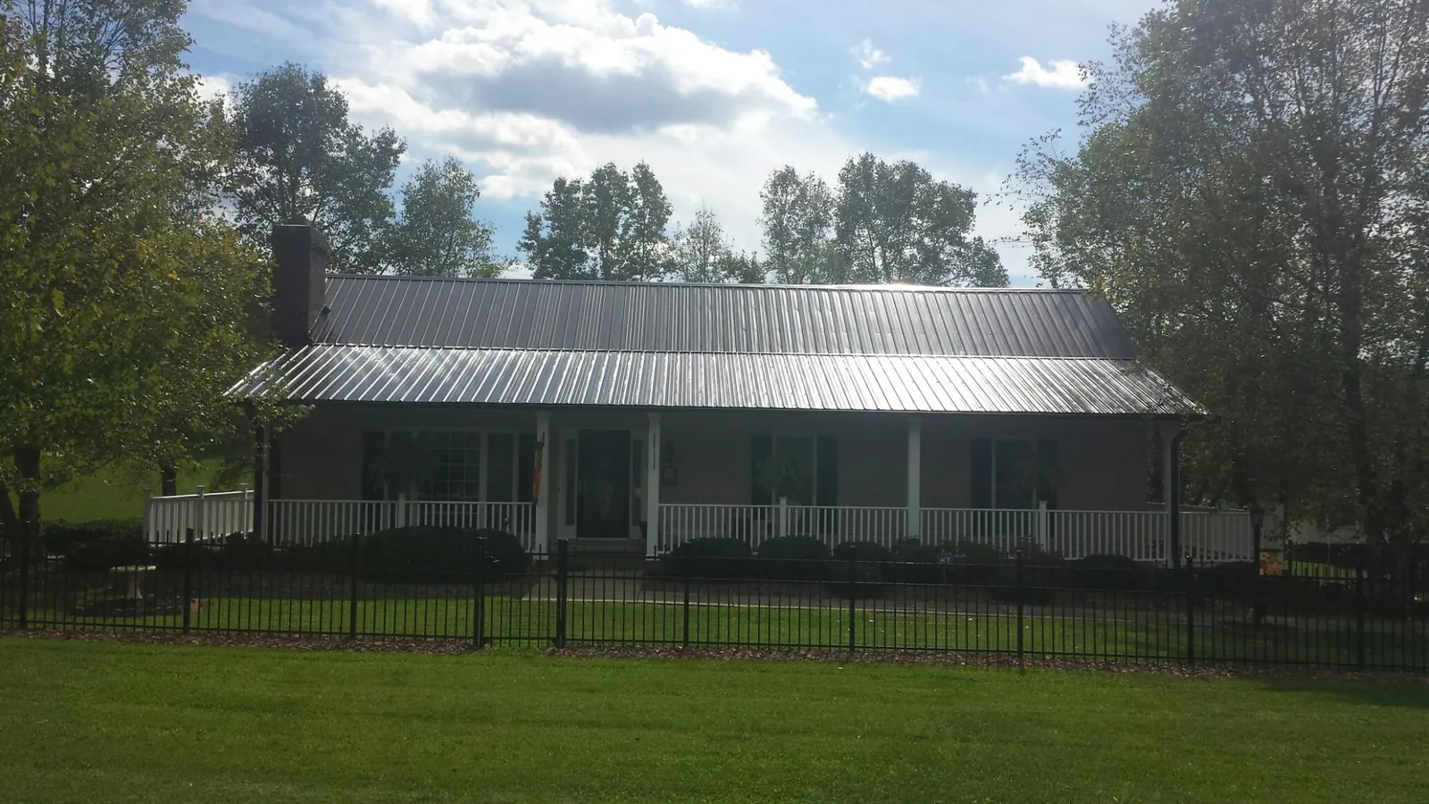 Gray metal roof on a brick ranch with a full width front porch — Gutter Guard Installation work by our crew in Brierfield