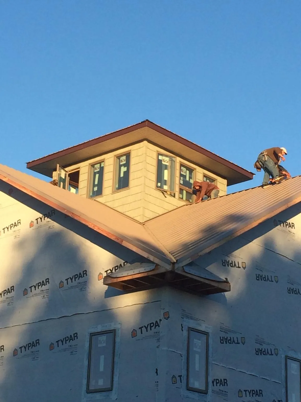 Roofers working around a rooftop cupola on a new metal roof at sunset — Roof Waterproofing in Brierfield by Roofing Brothers